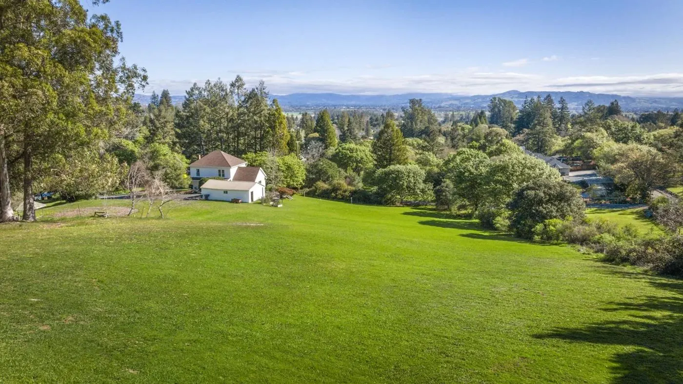 The sloping lawn of the property with the farmhouse and distant hills