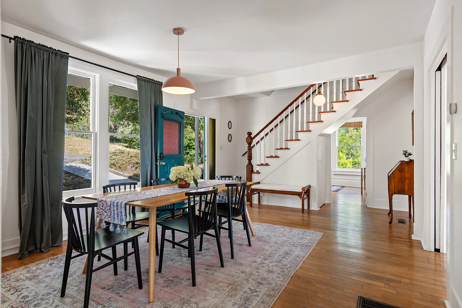 Dining room with a long wood table, original wood floors and the staircase beyond